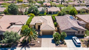 A residential area with houses featuring red-tiled roofs, surrounded by greenery and palm trees. - Tranquility in Trilogy (Peoria)