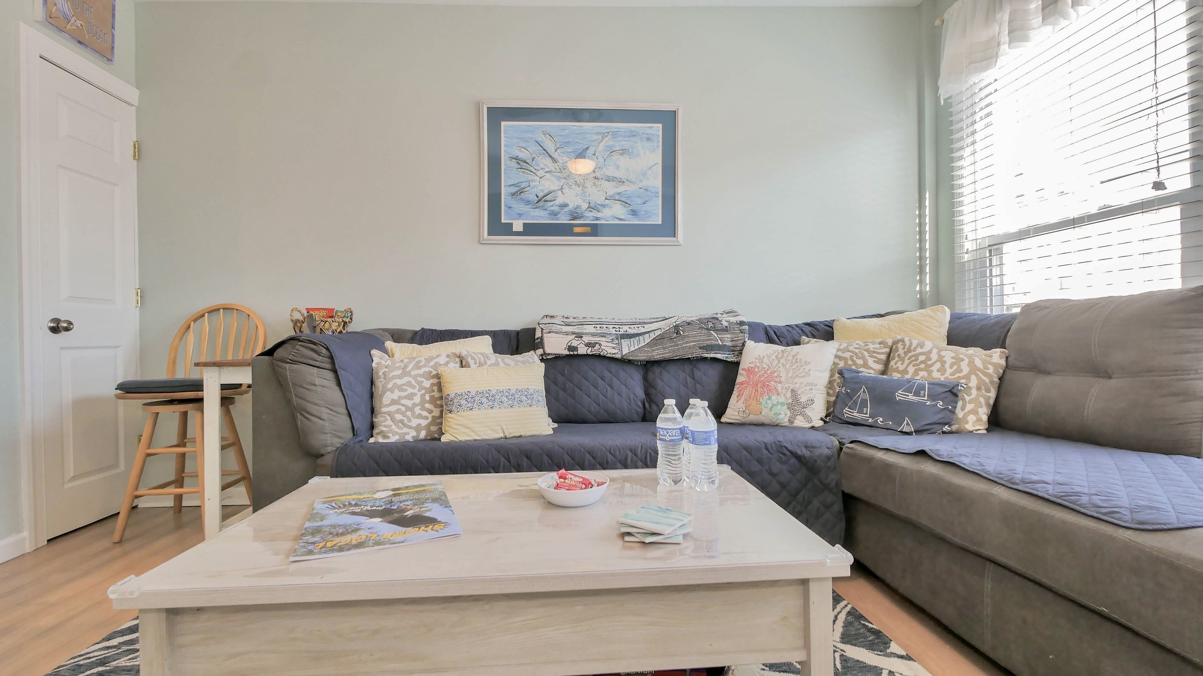 A living room with a sofa, a coffee table, and a framed artwork on the wall.