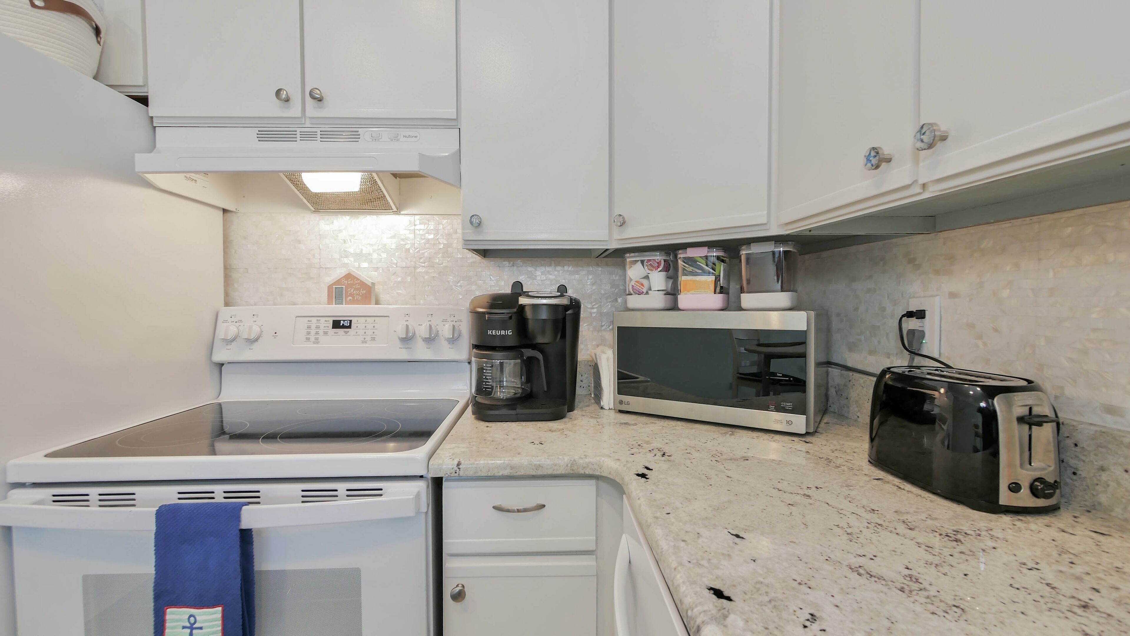 A kitchen with a stove, microwave, toaster, and a Keurig coffee maker.
