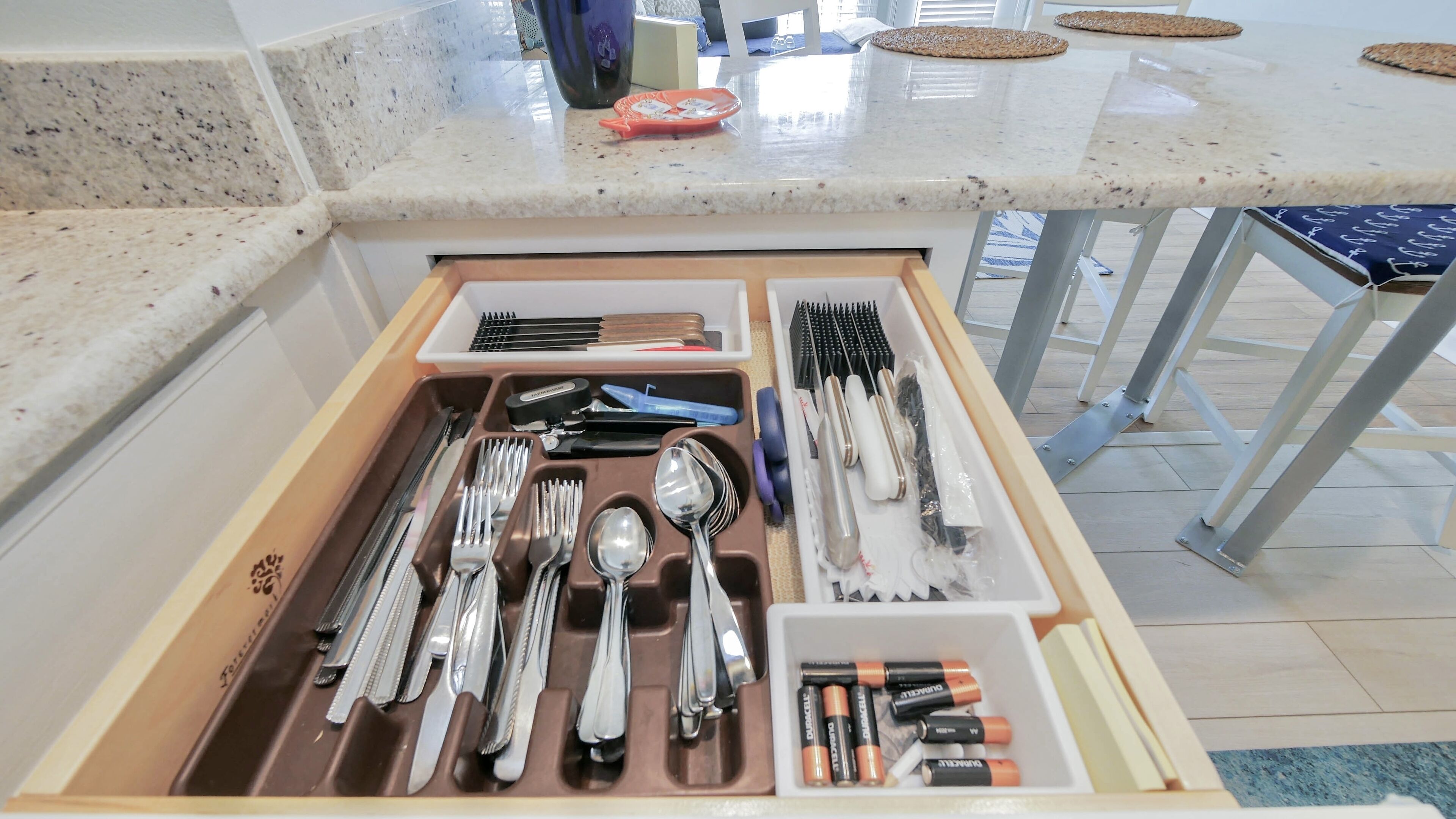 Un cajón de cocina con utensilios y pilas.
