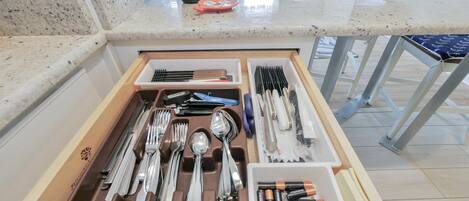 Un cajón de cocina con utensilios y pilas.