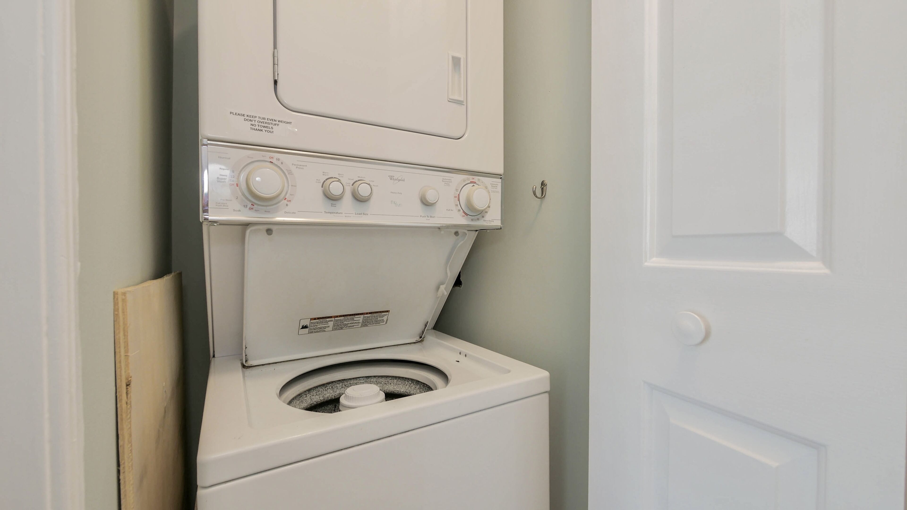 Un lave-linge et un sèche-linge à chargement frontal, installés dans une buanderie, avec une porte sur le côté droit.