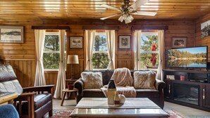 Un interior de cabaña acogedor con sofá, mesa de centro y televisor.