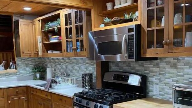 Una cocina con armarios de madera, estufa, microondas y tostadora.