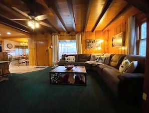 Relax in this inviting living room with a sofa set and coffee table, surrounded by framed pictures and a ceiling fan.