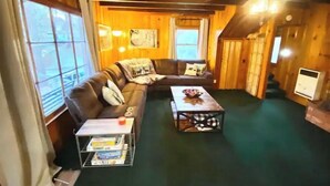 Interior acogedor de una cabaña con un sofá modular, una mesa de centro y una estantería.