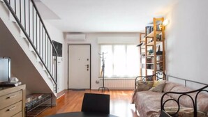 A modern living room with a staircase, a sofa, a coffee table, and a bookshelf. - VALSUGANA (Milan)