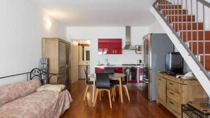A compact living space with a kitchenette, a dining area, and a staircase. - VALSUGANA (Milan)