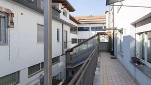 A narrow, covered pedestrian walkway between buildings with balconies and windows. - VALSUGANA (Milan)