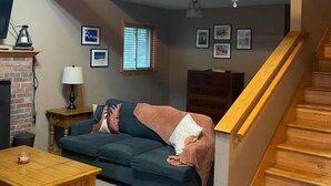 Un salon chaleureux avec un canapé bleu, une table basse en bois et un escalier doté de rampes en bois.