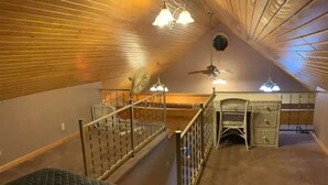 Une chambre à coucher aménagée dans un espace mansardé, avec un lit, un bureau et une chaise.