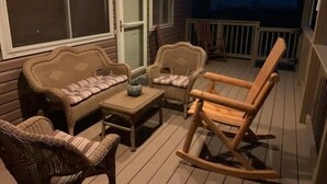 Un espace extérieur aménagé, abrité et doté de mobilier en osier, ainsi que d’un fauteuil à bascule.