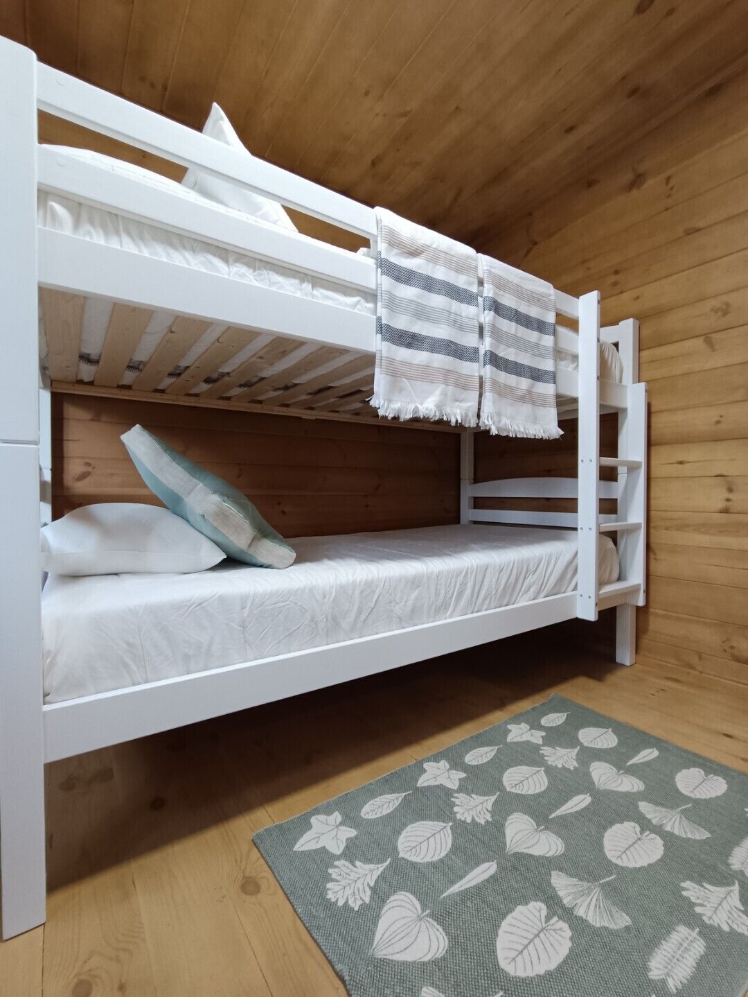 Ein Stockbett mit weißer Bettwäsche und einer Streifen-Decke.