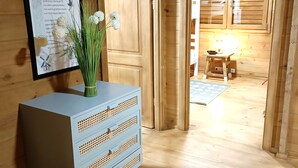 A wooden cabin interior with a blue dresser, a framed poem on the wall, and a small table with a lamp in the background. - Natura Fun House & Camping (Sintra)