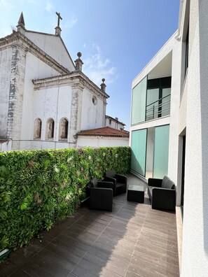 A balcony with dark wooden flooring, black outdoor furniture, and a green hedge. - RIA CENTRUM Smart Residence (Aveiro)