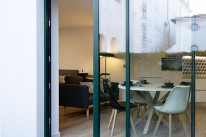 A modern dining area with a table and chairs, a sofa, and a lamp.