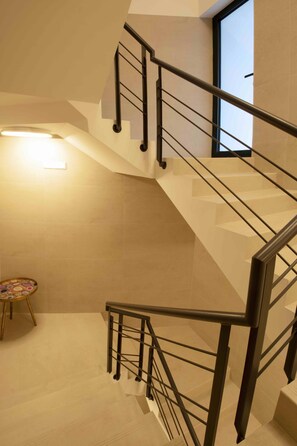 A modern staircase with a metal railing, a small table with a colorful pattern, and a window providing natural light. - RIA CENTRUM Smart Residence (Aveiro)