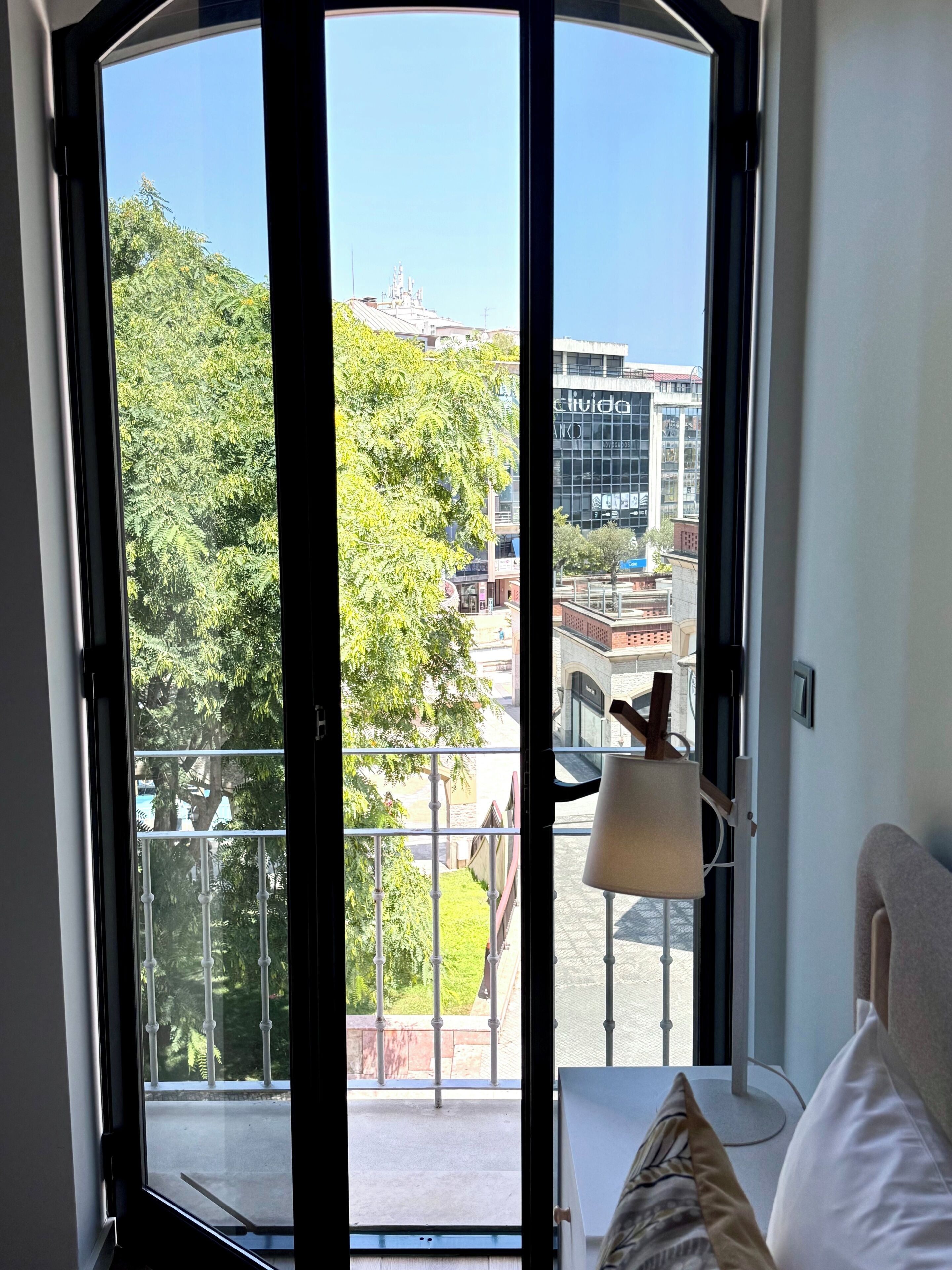 A room with a view of a balcony, a lamp, and a bed.