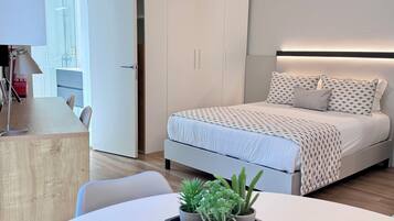 Ein modernes Schlafzimmer mit Bett, Nachttischen, Schreibtisch und einer Zimmerpflanze.