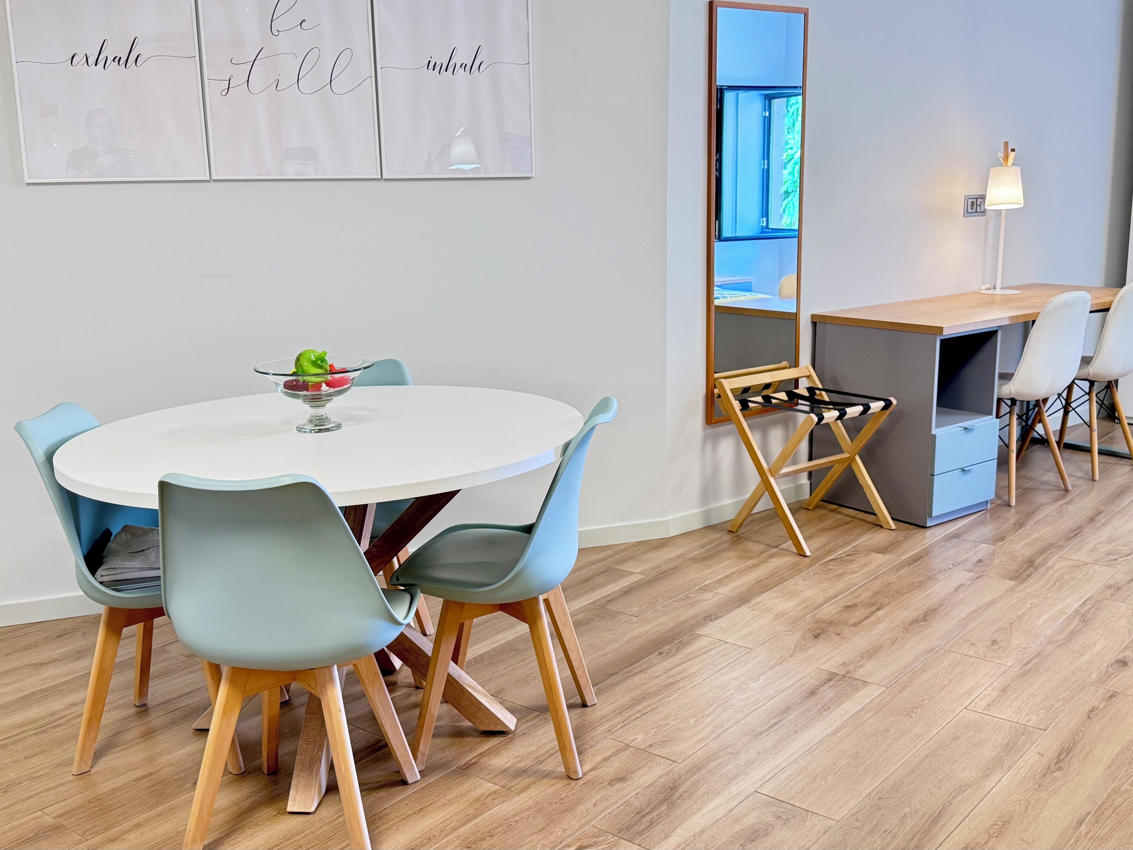 Un comedor moderno con una mesa redonda, sillas azul claro y un frutero pequeño.