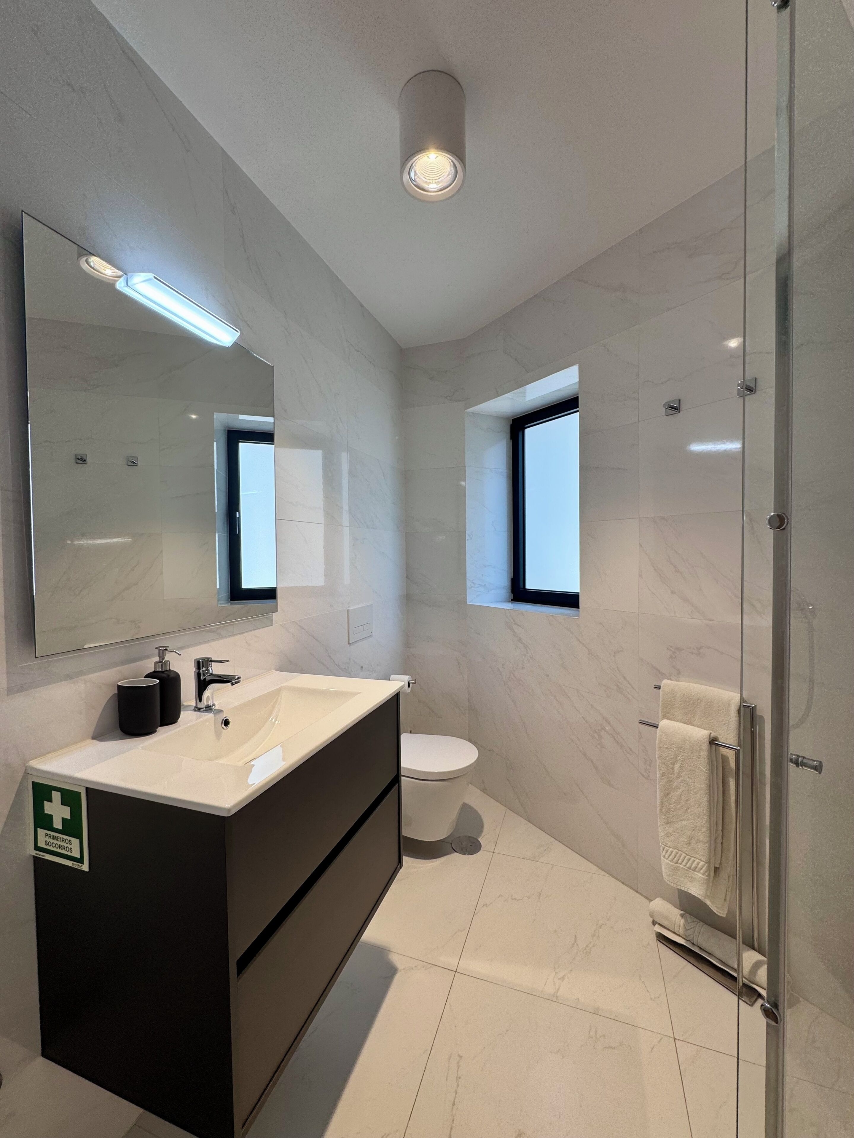 A modern bathroom with a large mirror, a sink, a toilet, and a shower area.