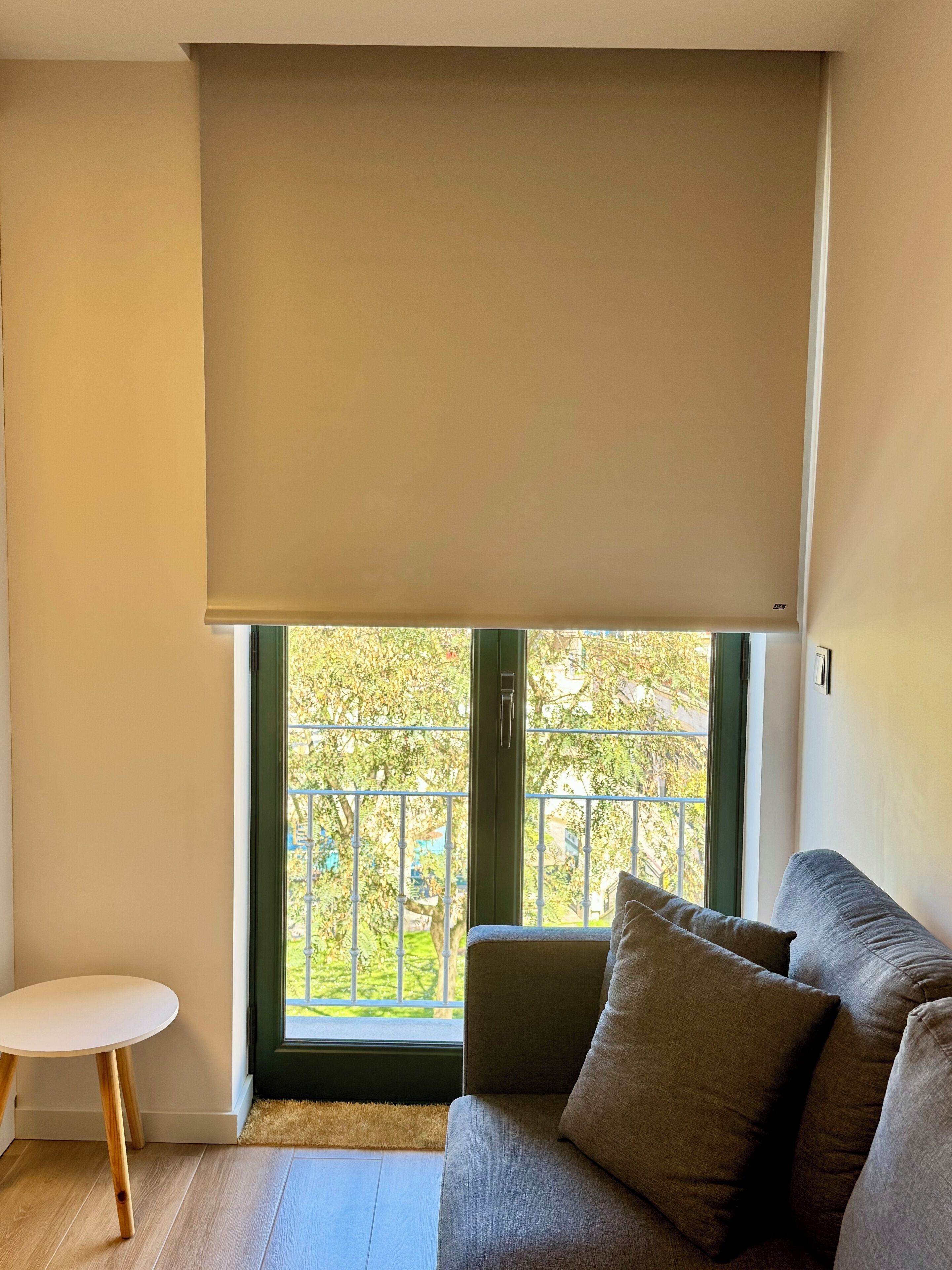 Una sala de estar con un sofá, una mesita redonda y un ventanal con vistas al verdor exterior.