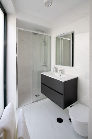 A modern bathroom with a glass shower enclosure, a white sink, and a large mirror. - RIA CENTRUM Smart Residence (Aveiro)