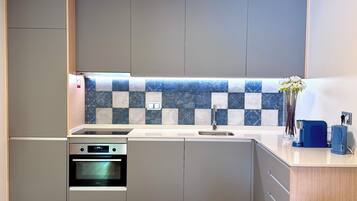 Uma cozinha moderna com armários cinza, uma moldura de backsplash estampada, forno embutido e pia.