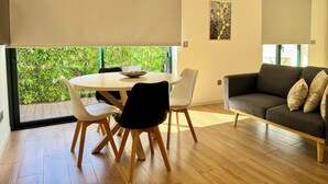 Un salon moderne avec une table à manger ronde, des chaises blanches et un canapé gris foncé.
