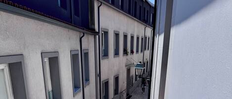 A narrow alleyway between buildings with a metal railing on one side.