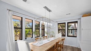 A dining area with a wooden table, chairs, and a hanging light fixture. - Wildlife viewers dream! Peaceful & so clean, golf cart incl., pool across street (Fripp Island)