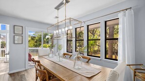 A dining area with a wooden table, chairs, and a hanging light fixture. - Wildlife viewers dream! Peaceful & so clean, golf cart incl., pool across street (Fripp Island)