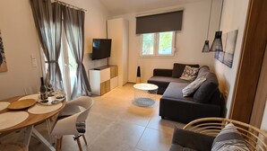 Ein modernes Wohnzimmer mit einer Couch, einem Esstisch mit Platzsets, einem Fernseher und Kunstwerken an den Wänden.