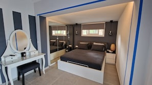 Een slaapkamer met een bed, een bureau met spiegel en een dressoir.