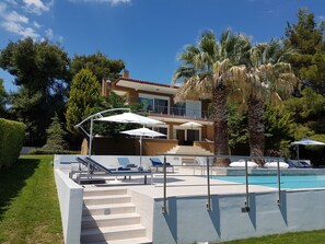 A modern house with a swimming pool, outdoor seating, and a staircase leading to the pool area.