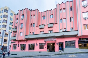 Un edificio rosa con múltiples ventanas y balcones, que presenta una tienda con un letrero que dice