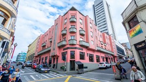 A pink hotel with balconies, located on a busy street corner. - Hotel Escorial (Manizales)
