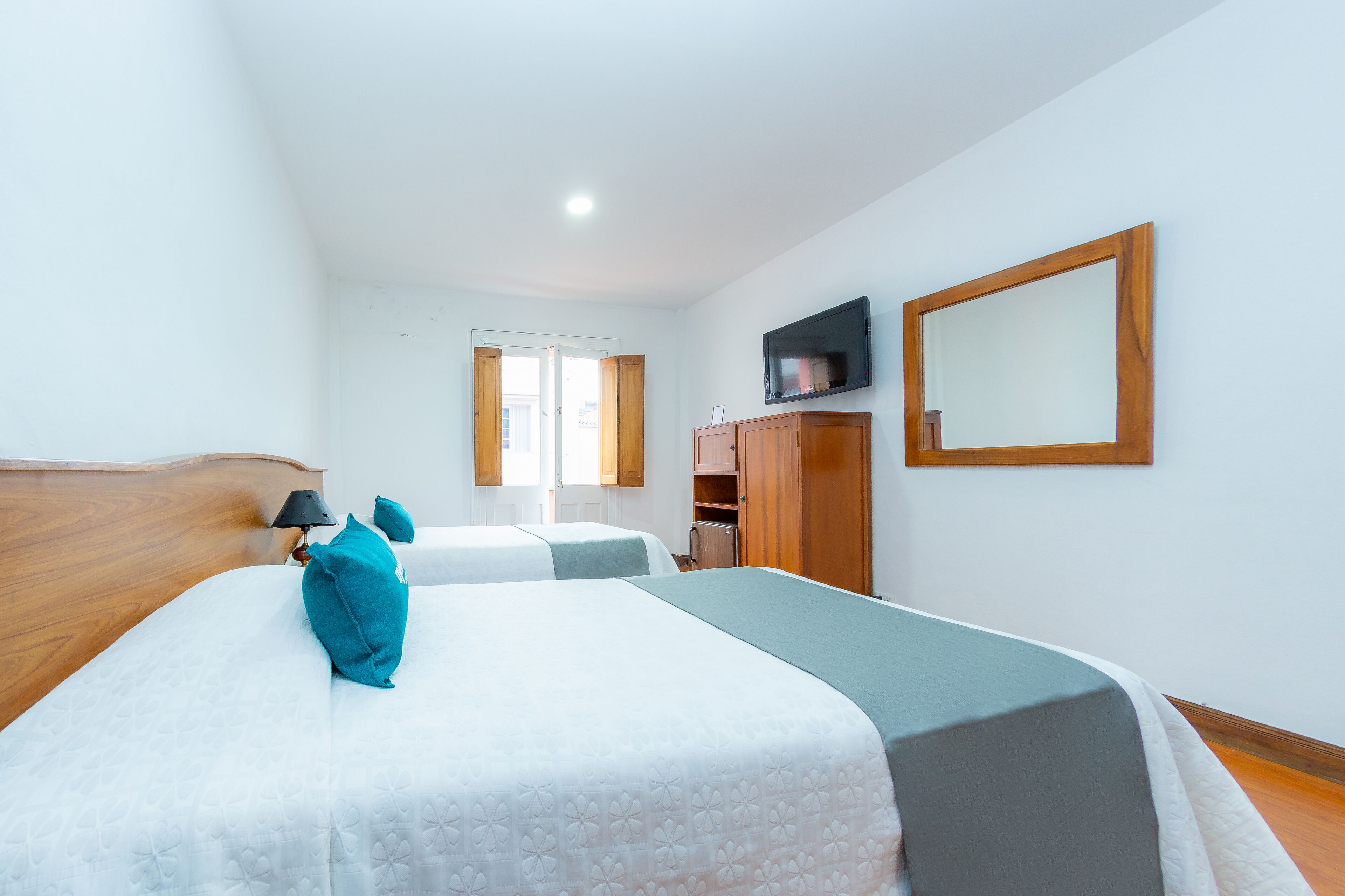 A hotel room with two beds, a television, a wardrobe, and a door leading to a balcony.