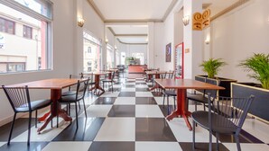 A hotel lobby with a checkered floor, wooden tables, and chairs. - Hotel Escorial (Manizales)