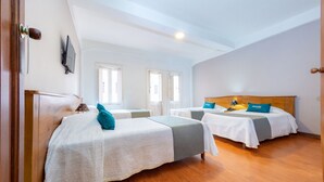 A hotel room with two beds, wooden flooring, and a TV on the wall. - Hotel Escorial (Manizales)