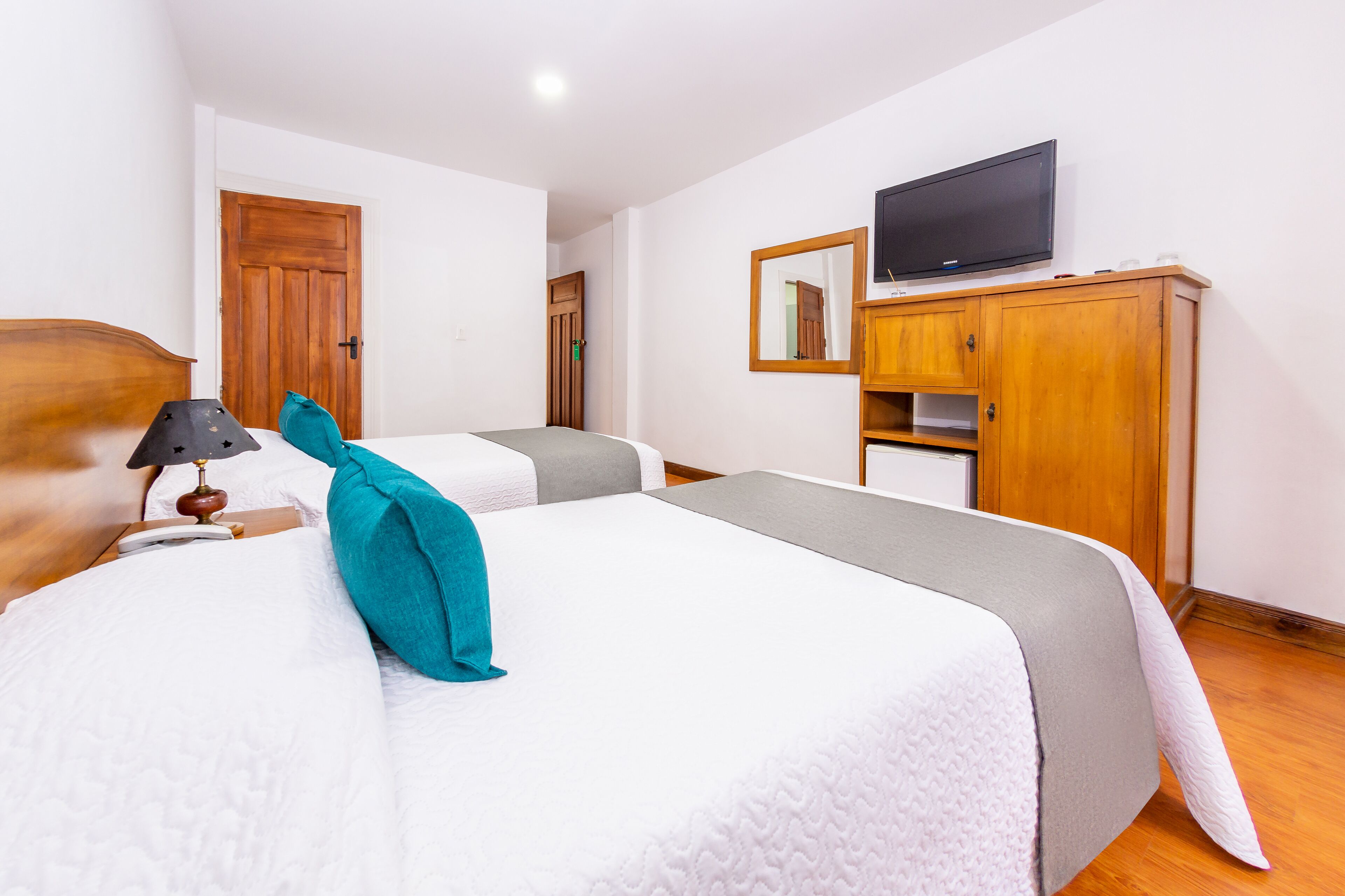 A hotel room with two beds, a television, a wardrobe, and a door.