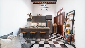 A compact kitchen with a bar stool area, a refrigerator, and a bookshelf. - Quiet 2BR Loft • Walk Everywhere • King & Queen Beds • Open Layout (San Juan)