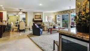 A spacious living area with a fireplace, comfortable seating, and a dining area. - Comfortable, modern condo located steps from the beach! (Oceanside)