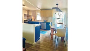 Una cocina moderna con una isla central, suelo de madera y un comedor con mesa y sillas.