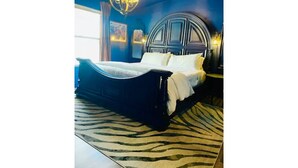 Un dormitorio con una cama grande, un tapete estampado de cebra y una araña.