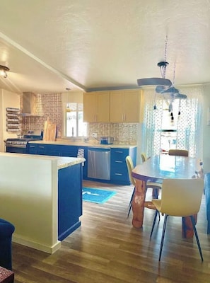 Une cuisine moderne dotée d’un îlot central, d’un plancher en bois et d’un coin repas avec une table et des chaises.