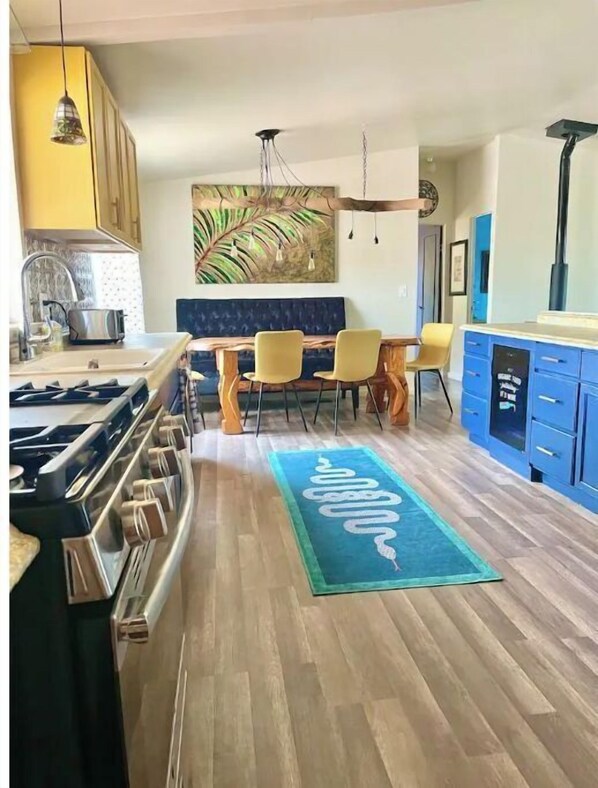 Una cuina moderna amb forlla de gas, armaris de fusta i zona de menjador amb una alfàbria blava.