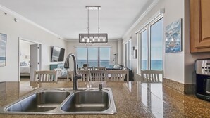 A kitchen with a double sink, a dining area with a view, and a large window.