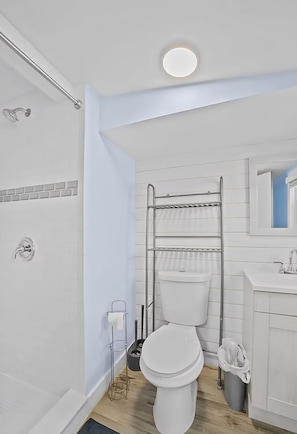 A modern bathroom with a shower, toilet, and sink.