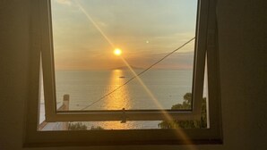 Ein Sonnenuntergang durch ein Fenster, wobei sich die Sonne auf dem Wasser spiegelt.